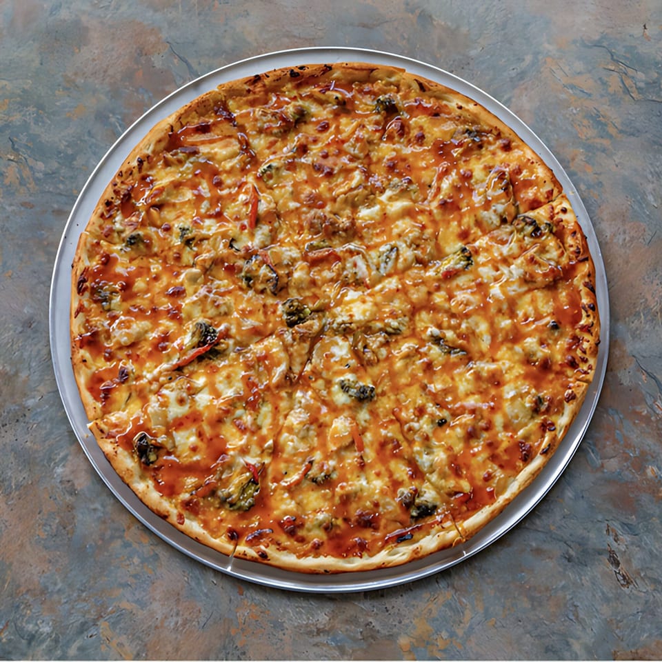D-Ray's Pizzeria's whole pizza with melted cheese, toppings, and a sweet glaze on a metal pan.