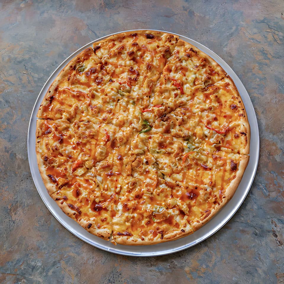 A whole D-Ray's Pizzeria BBQ chicken pizza, sliced and drizzled with sauce on a metal pan.